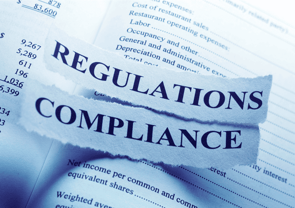 orn paper strips with the words 'Regulations' and 'Compliance' placed over a financial document, symbolizing betting laws and regulations in Europe